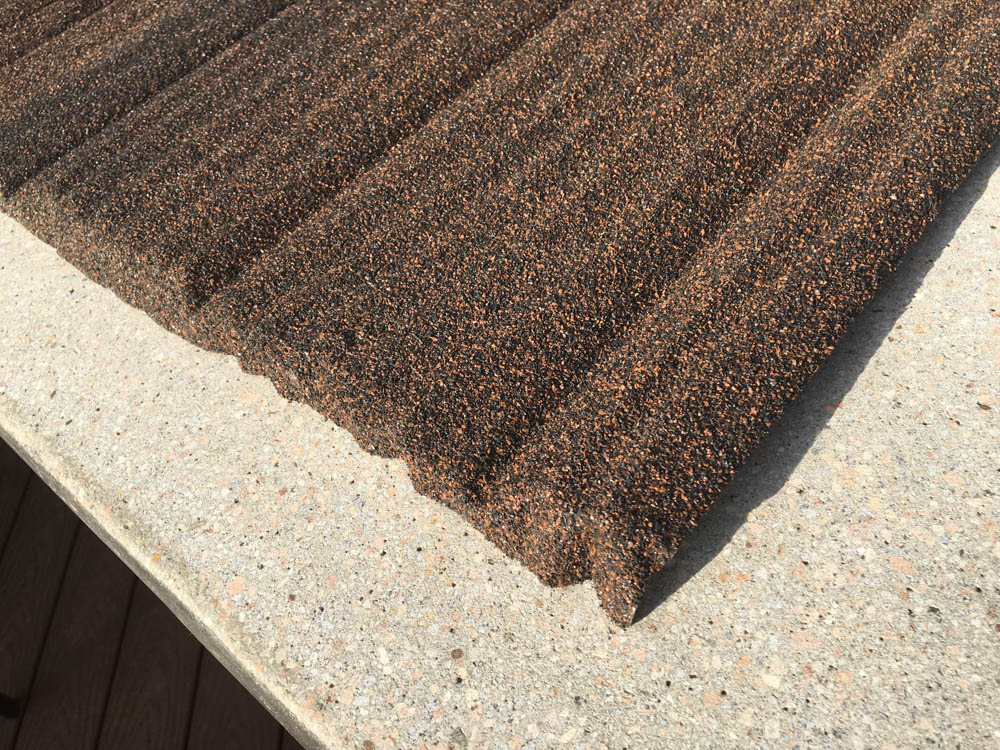 close-up of top of new residential stone-coated metal roofing shingle