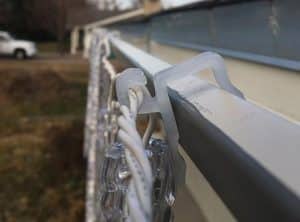 christmas lights attached to gutter clip hanging from gutter